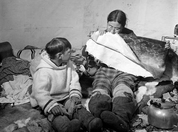 Inuit vrouw met bril maakt zeehondenhuid soepel door erop te kauwen