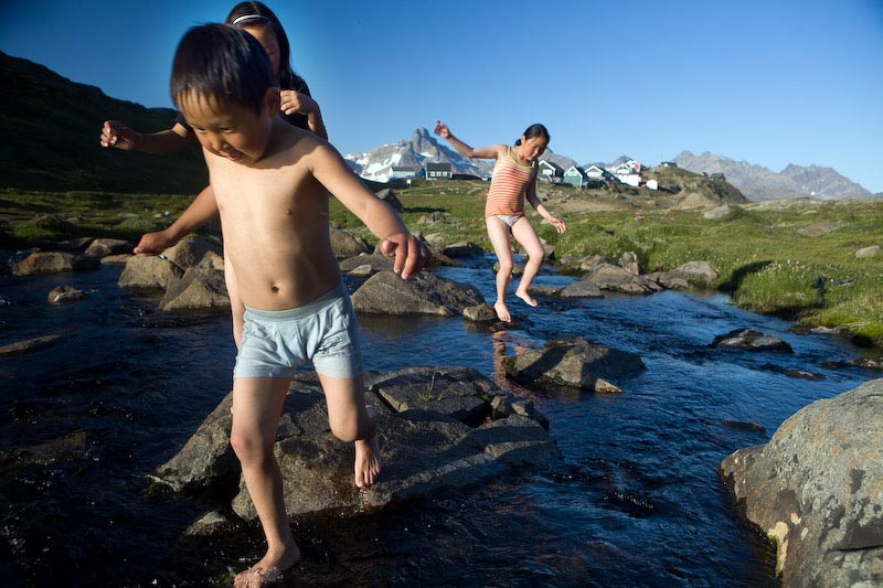 Spelen in beekjes smeltwater, in Tasiilaq vlakbij Ittimiini